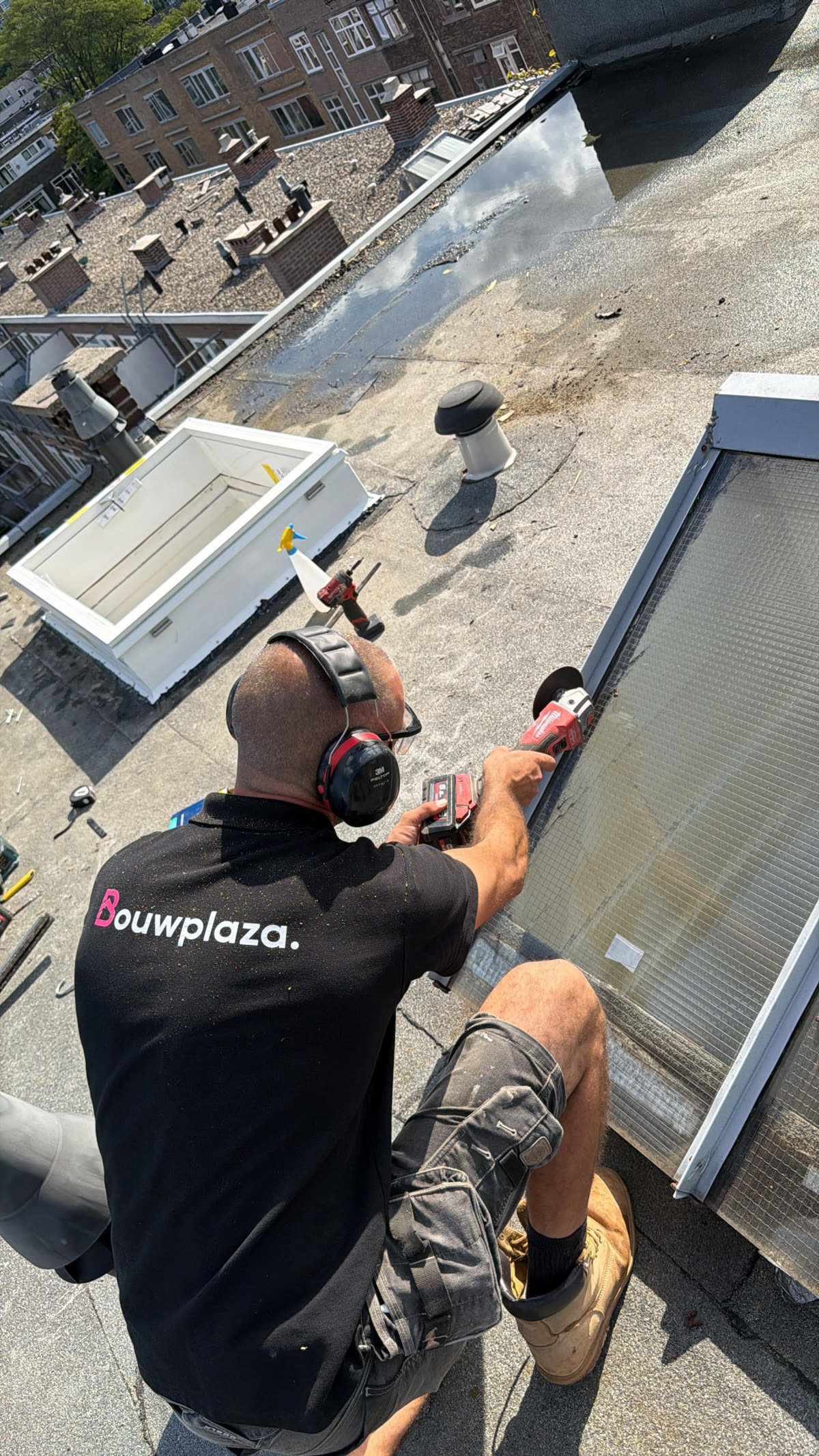 Bouwplaza monteur zaagt een sparing voor een nieuw dakraam